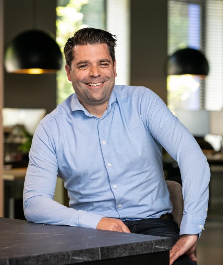 Man in blauwe blouse lacht in kantooromgeving