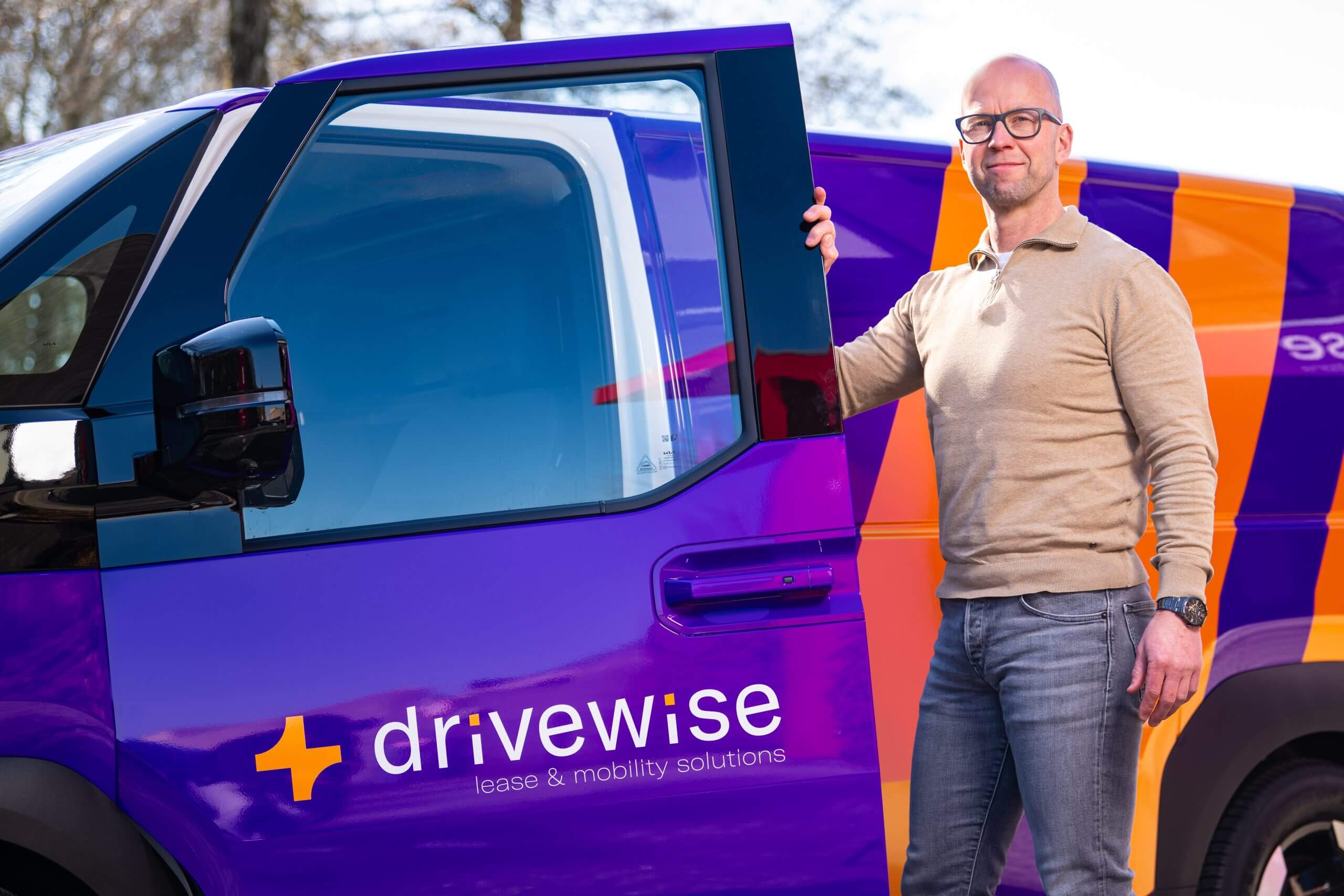 Man opent paarse bestelwagen met Drivewise-logo.